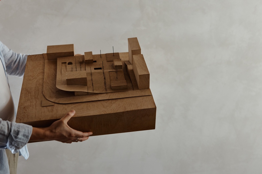 Person holding cardboard architectural model.
