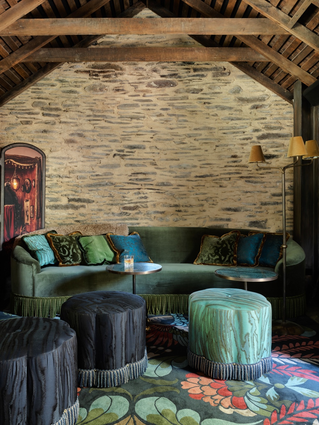 Schist stone wall and a fringed green velvet sofa in the Burr Bar.