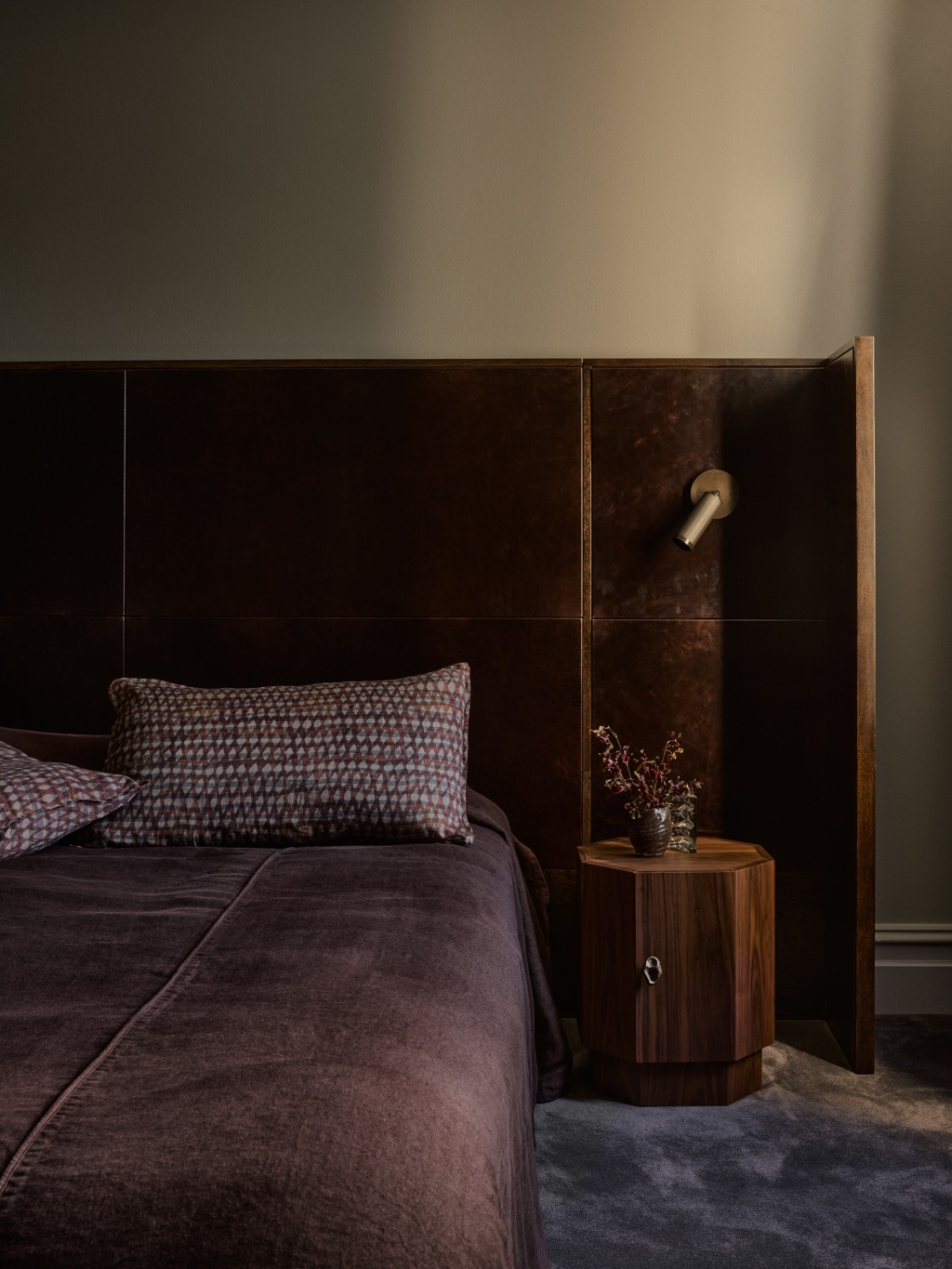 Master bedroom with a leather upholstered bedhead and timber side table.